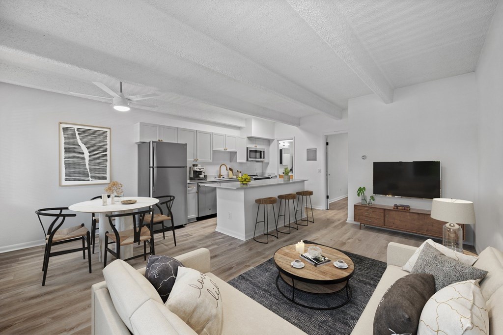 A modern living room with a kitchen in the background.