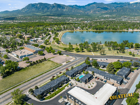 an aerial view of a building with a lake and mountains in the background