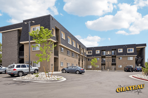 a parking lot with cars in front of an apartment building