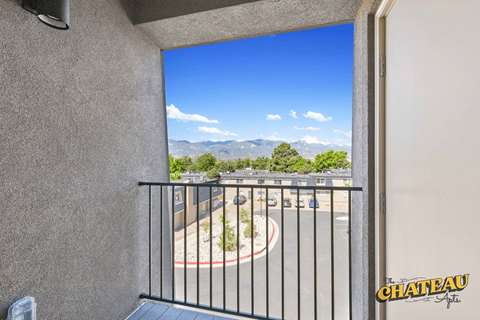 a balcony with a view of a parking lot and mountains
