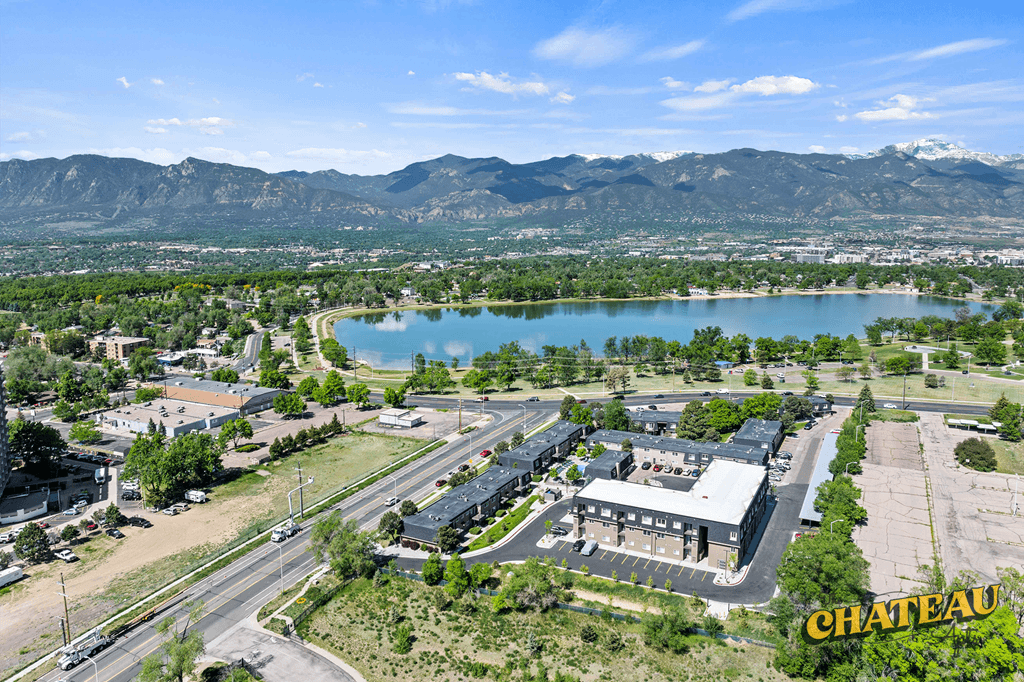 an aerial view of a building with a lake and mountains in the background