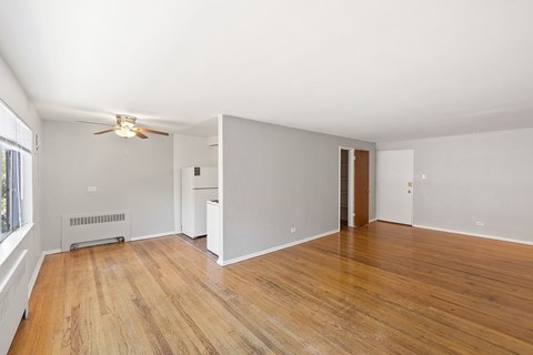 A room with a ceiling fan and a wood floor.
