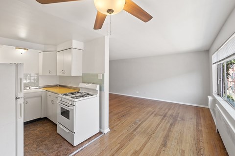 A kitchen with white appliances and wooden floors.