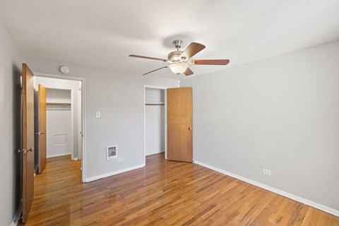 A room with a ceiling fan and wooden floors.