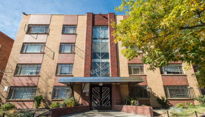 A red brick building with a black gate in front.