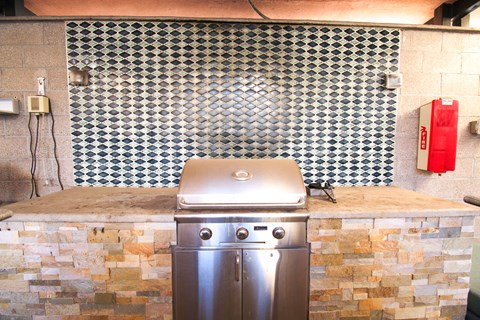 A stainless steel dishwasher is in front of a stone backsplash.