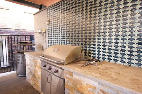 A stainless steel grill is on a stone countertop.