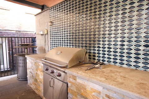 A stainless steel grill is on a stone countertop.