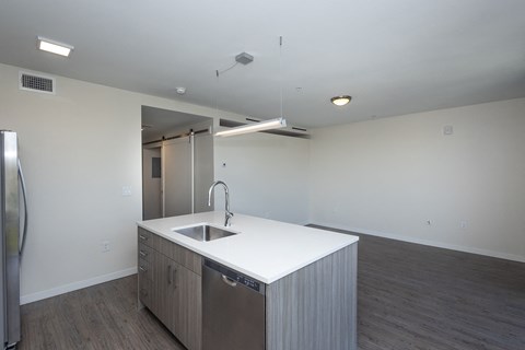 an empty kitchen with a white counter top and a stainless steel refrigerator