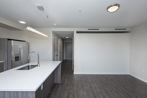 an empty kitchen with white countertops and a stainless steel refrigerator
