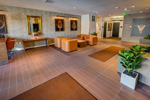 a lobby with yellow tables and chairs and a wall with paintings