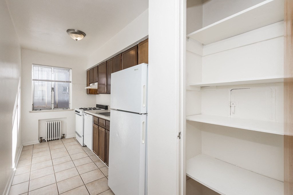 A kitchen with white appliances and brown cabinets.