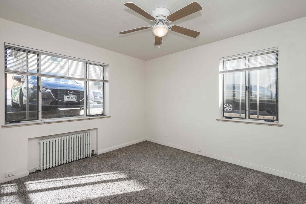 A room with a ceiling fan and two windows.
