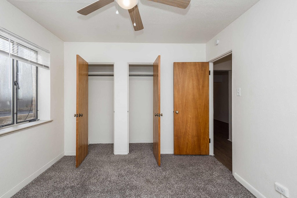 A room with a ceiling fan and two doors.