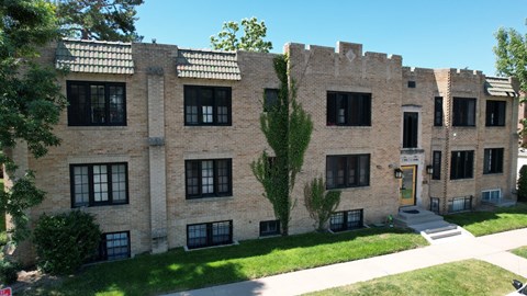 an old brick building with black windows and a lawn