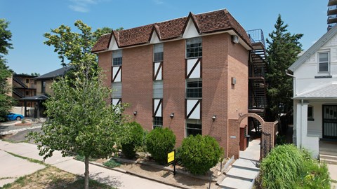 A red brick building with white trim and a black iron gate.