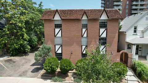 A red brick building with white trim and a black gate.