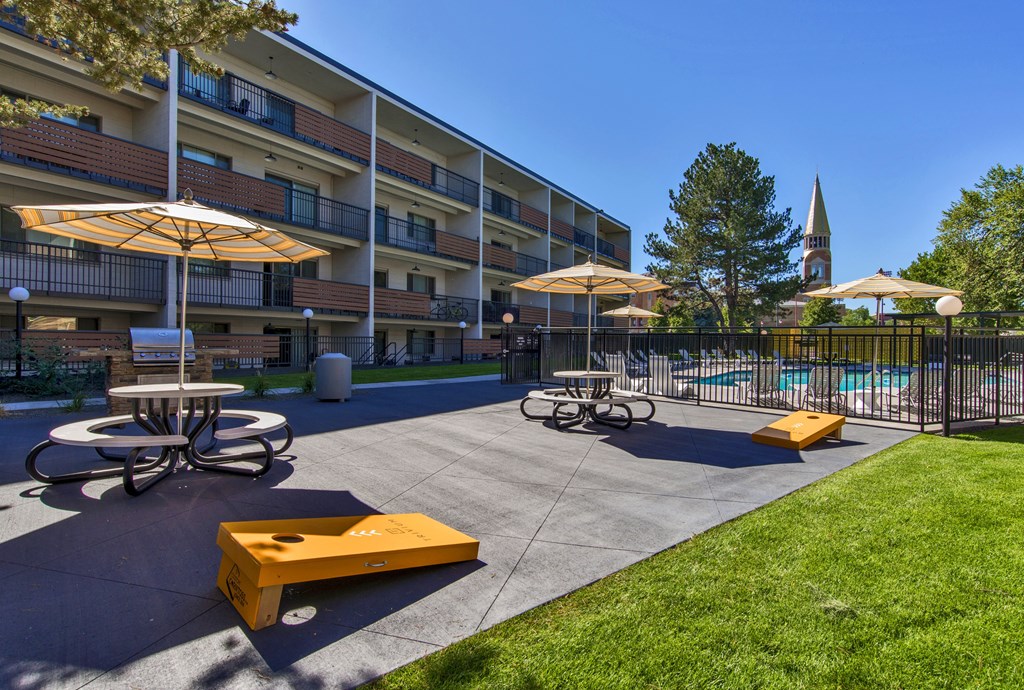 A sunny day at the apartment complex with a pool and picnic tables.