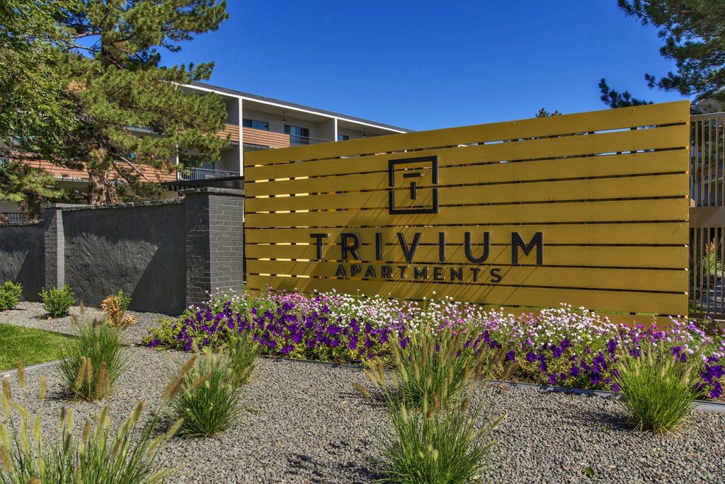 A sign that says Trivium Apartments in front of a building.