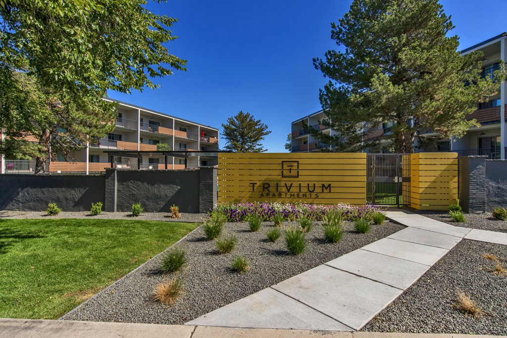 A yellow sign with the word "TRIVIUM" on it is in front of a building.