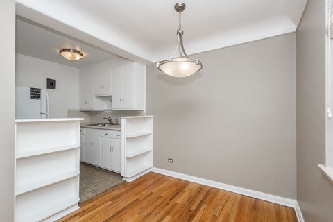 A kitchen with white cabinets and a wooden floor.