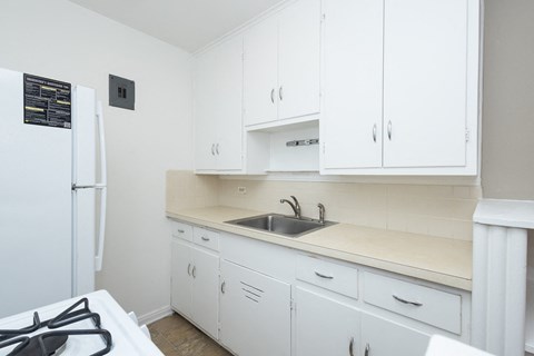 A kitchen with white cabinets and a black fridge.