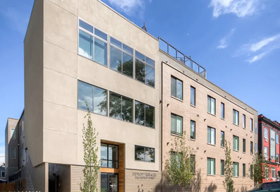 A modern building with a beige facade and large windows.