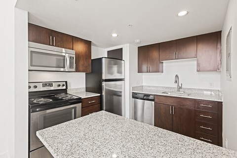 A kitchen with a granite countertop and stainless steel appliances.