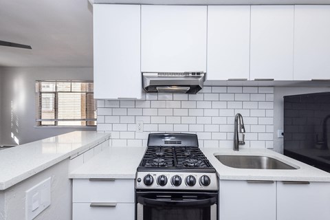 A modern kitchen with a black stove top oven and white cabinets.