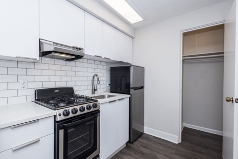 A kitchen with white cabinets and a black stove top oven.