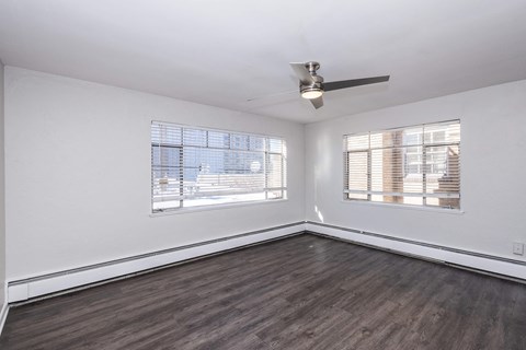 A room with a ceiling fan and two windows.