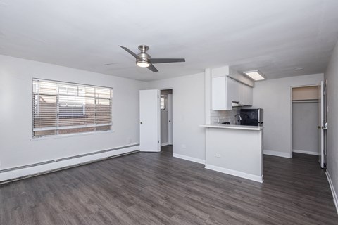 A spacious room with a ceiling fan and wooden flooring.