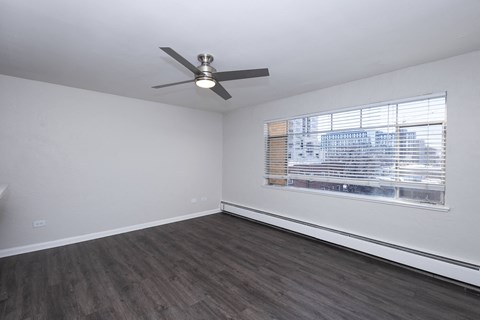 A room with a ceiling fan and a window with blinds.