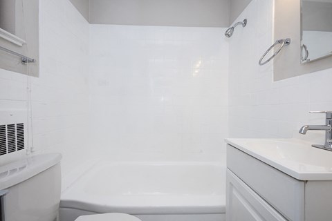 A white bathroom with a tub, sink, and mirror.