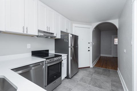 A kitchen with white cabinets and a stainless steel refrigerator.