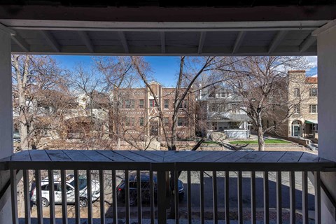 A view from a balcony overlooking a parking lot and apartment buildings.