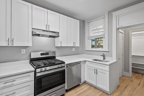 A modern kitchen with white cabinets and a stainless steel oven.