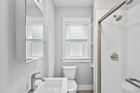 A white bathroom with a toilet, sink, and window.