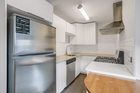 A modern kitchen with a stainless steel refrigerator and white cabinets.
