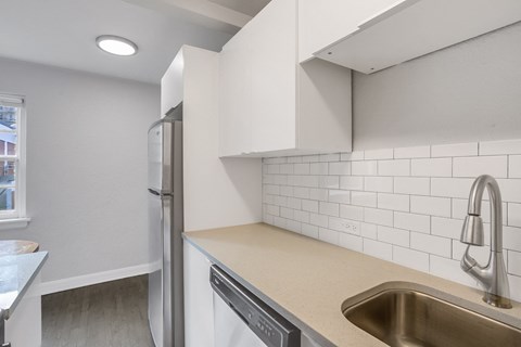 A kitchen with a stainless steel sink and white cabinets.