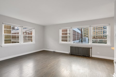 A room with a window overlooking a cityscape and a radiator on the floor.