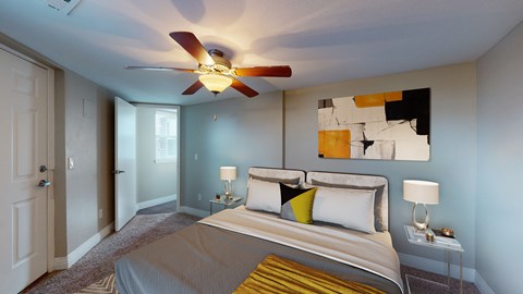A bedroom with a bed, two lamps, and a ceiling fan.