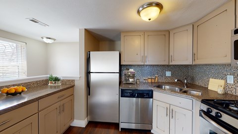 A kitchen with a refrigerator, stove, and sink.
