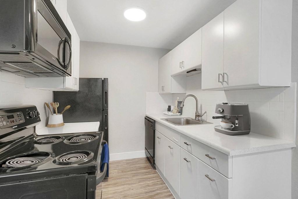 a white kitchen with black appliances and white cabinets