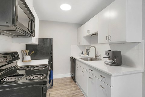 a kitchen with white cabinets and black appliances