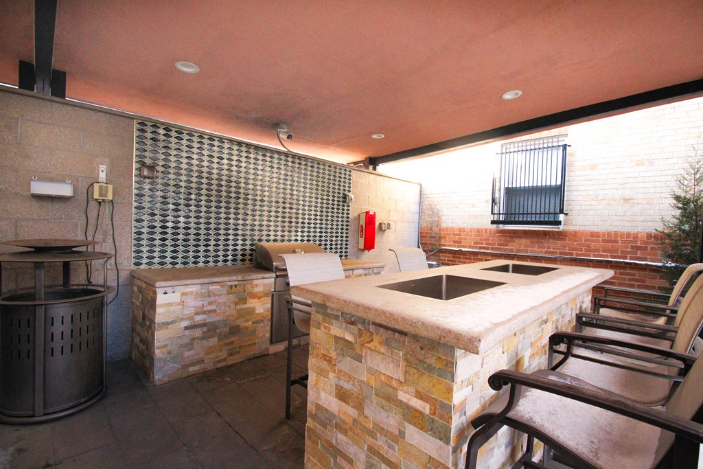 A patio with a stone counter and chairs.