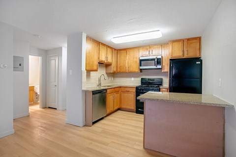A kitchen with wooden cabinets and a black fridge.