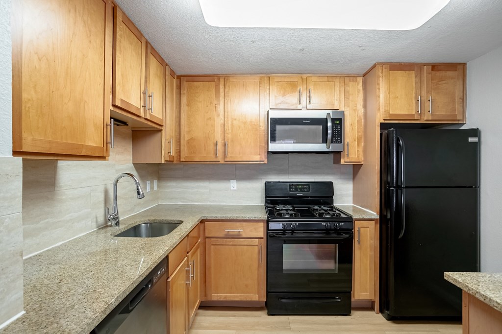 A kitchen with wooden cabinets and black appliances.