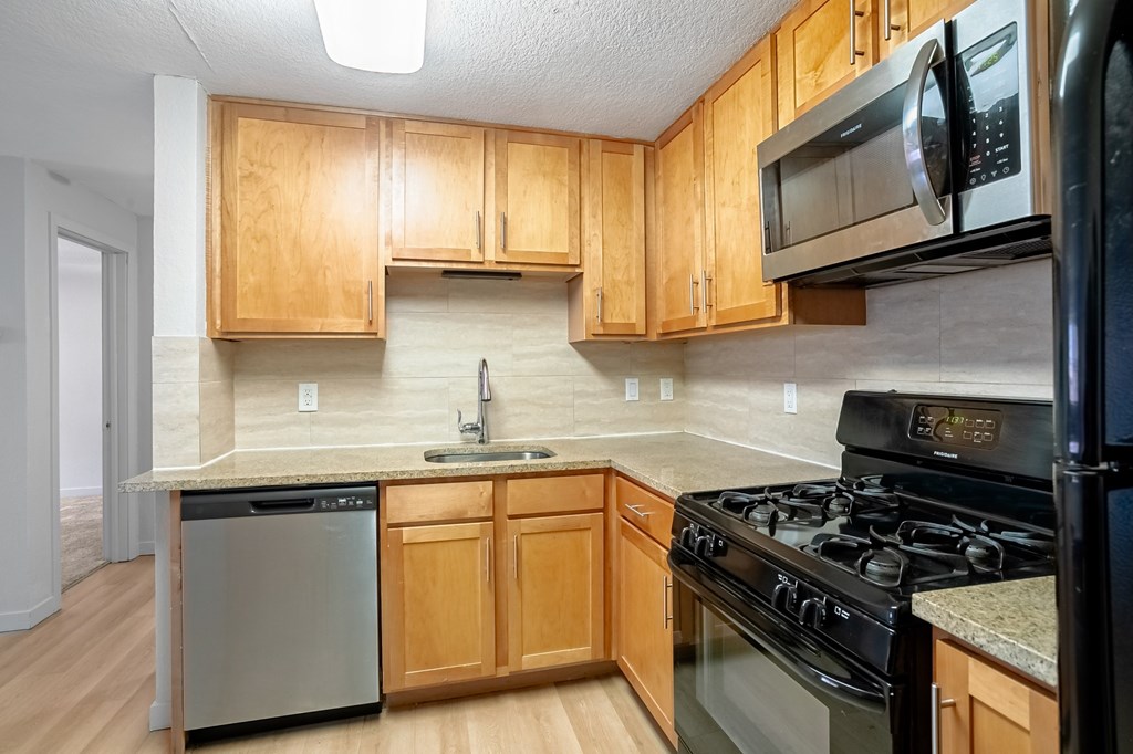 A kitchen with wooden cabinets and black appliances.