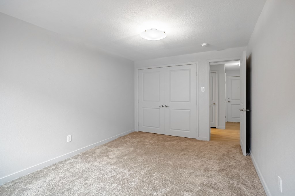 A room with a carpeted floor and a white door.